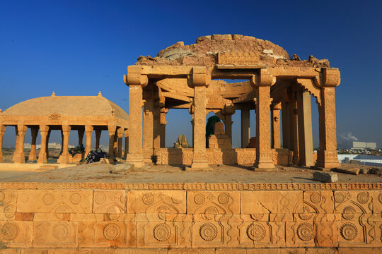 View of the historic Chaukhandi tombs featuring intricate sandstone carvings and ancient funerary architecture under a clear blue sky in Karachi, Sindh, Pakistan.