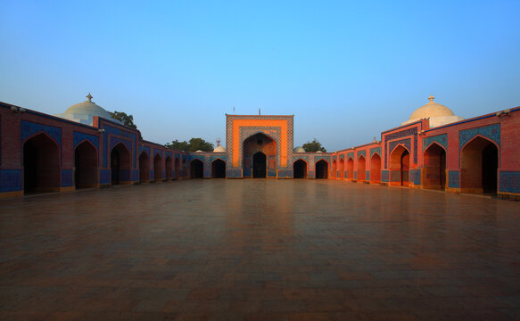View of the historic Shah Jahan Masjid with its intricate blue tile work and brick arches surrounding a spacious courtyard in Thatta, Sindh, Pakistan.