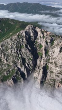 Vertical 4K UHD Drone Flight Over Massive Rocky Cliffs Rising Through a Sea of Clouds.