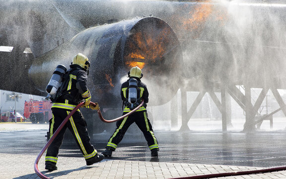 View of two firefighters in protective gear using high-pressure hoses to extinguish a fire in an aircraft engine in Badhoevedorp, Noord-Holland, Netherlands.