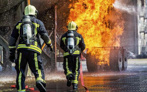View of two firefighters in protective gear and oxygen tanks extinguishing a large fire with water hoses at Sloterweg 527 in Badhoevedorp, Noord-Holland, Netherlands.