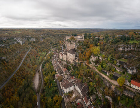 Aerial view of the historic village of Rocamadour built into the limestone cliffside with medieval buildings and winding roads in Rocamadour, Occitanie, France.