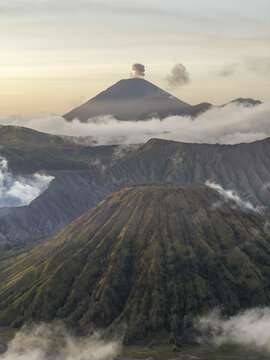 Aerial view of Mount Bromo with volcanic craters, rugged terrain, and clouds at sunrise in Tosari, East Java, Indonesia.