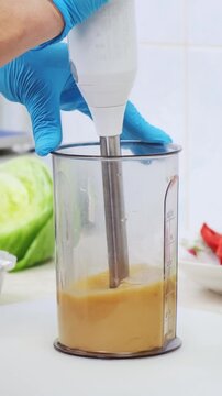Cook woman in restaurant kitchen make homemade sweet and sour sauce for olive oil salad dressing. Professional chef mix ingredients in blender bowl. Healthy and diet food delivery concept. 4K footage