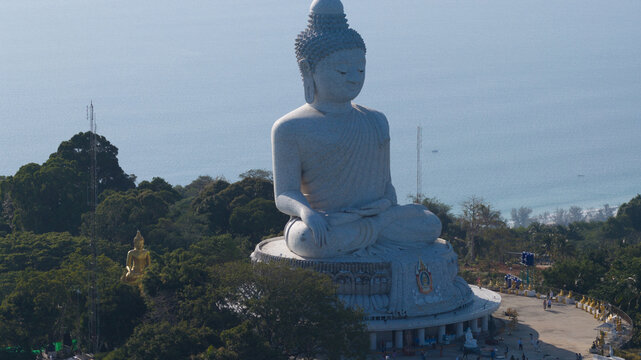 Aerial view of the Big Buddha Phuket, a large white marble statue overlooking the lush green hills and the coastline of Karon, Phuket, Thailand.
