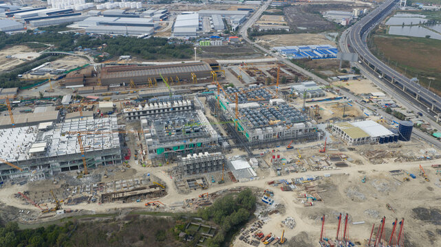 Aerial view of Bridge Data Center construction site with multiple buildings, industrial cranes, and adjacent highway in Khlong Tamru, Chon Buri, Thailand.