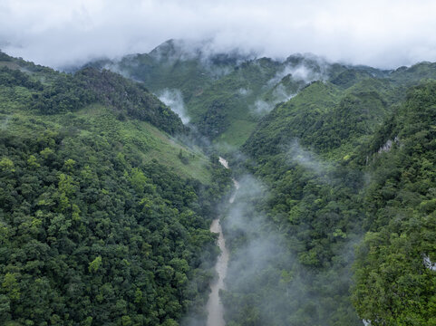 Aerial view of the lush green mountains and the winding river of Semuc Champey shrouded in mist in San Agustin Lanquin, Alta Verapaz Department, Guatemala.
