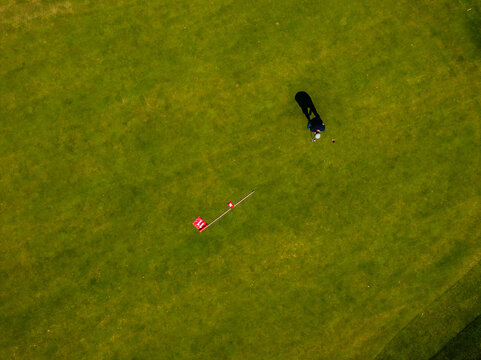 Aerial view of a golfer standing on a putting green near the red flag marked with number 11 in Baden-Wurttemberg, Germany.
