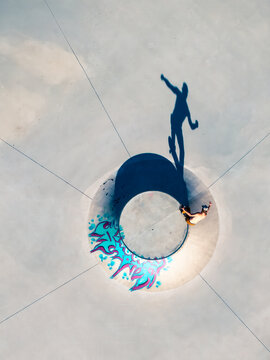 Aerial view of a skateboarder riding in a concrete bowl with colorful graffiti at a skatepark in Mannheim, Baden-Wurttemberg, Germany.