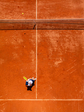 Aerial view of a tennis player standing on a clay court with a racket in hand, captured from directly above in Mannheim, Baden-Wurttemberg, Germany.