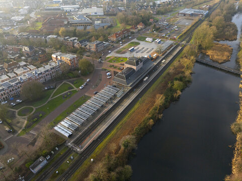 Aerial view of the railway station with its platforms, tracks, and adjacent parkland alongside a river in Sneek, Friesland, Netherlands.