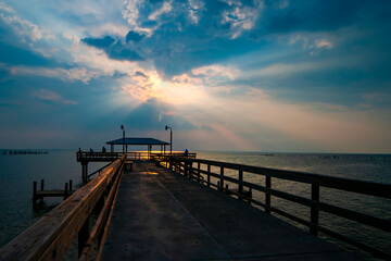 Fototapeta premium Sunset at pier with Silhouette people relaxing and enjoying the view over water