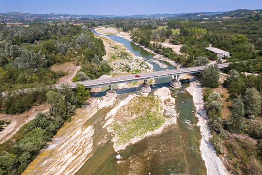 Aerial view of the Tanaro river suffering from severe drought with exposed riverbed and a bridge crossing the water in Alba, Piedmont, Italy.