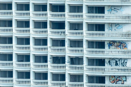 Aerial view of the repetitive white balconies of a high-rise building facade featuring urban graffiti in Bangkok, Bangkok, Thailand.