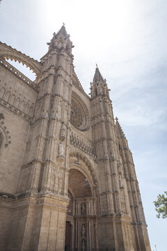 View of the Gothic facade of the Cathedral of Santa Maria of Palma, also known as La Seu, with intricate stone carvings and a rose window in Palma, Balearic Islands, Spain.