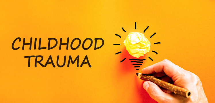 Childhood trauma words symbol. Concept words Childhood trauma on beautiful orange paper. Beautiful orange background. Psychologist hand. Psychological childhood trauma support concept. Copy space.