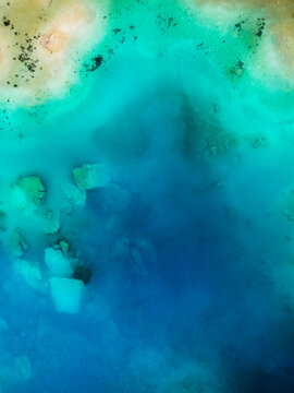 Aerial view of a vibrant turquoise alpine lake with rocky shoreline and clear water in Grisons, Switzerland.