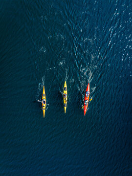 Aerial view of three colorful kayaks paddling on the deep blue waters of Lake Constance in Thurgau, Switzerland.