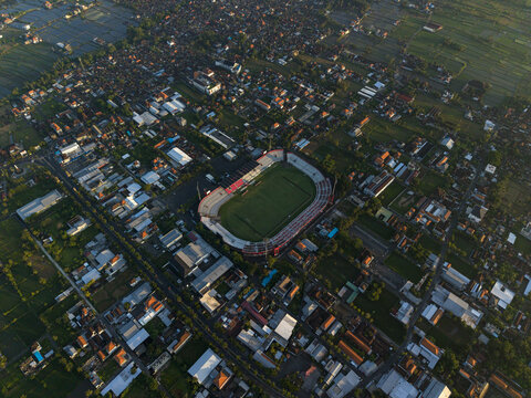 Blahbatuh, Indonesia - 03 July 2026: Aerial view of Kapten I Wayan Dipta Stadium surrounded by residential rooftops, rice fields, and urban infrastructure.