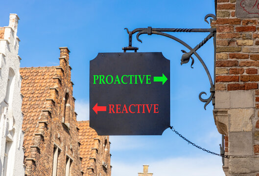 Proactive and reactive symbol. Concept word Proactive Reactive on beautiful black road sign. Beautiful blue sky and Brugge street background. Business proactive and reactive concept. Copy space.