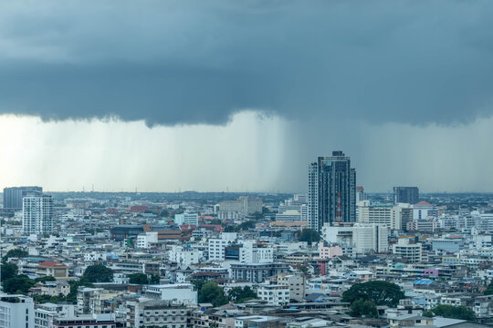 Aerial view of the cityscape of Bangkok under a dramatic dark storm cloud with heavy rain falling over the urban skyline in Bangkok, Bangkok, Thailand.