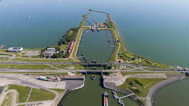 Aerial view of the Kornwerderzand locks on the Afsluitdijk, featuring concrete infrastructure, calm water, and green embankments in Kornwerderzand, Friesland, Netherlands.