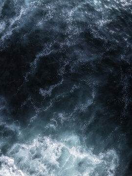 Aerial view of deep blue ocean waves with white sea foam crashing on the surface in San Diego, California, United States.
