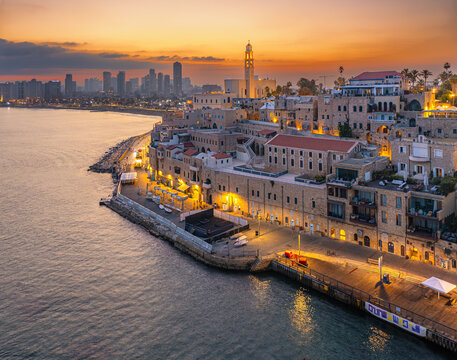 Aerial view of Jaffa Port at sunset with historic stone buildings along the Mediterranean coastline and the Tel Aviv skyline in the distance, Tel Aviv-Jaffa, Tel Aviv District, Israel.
