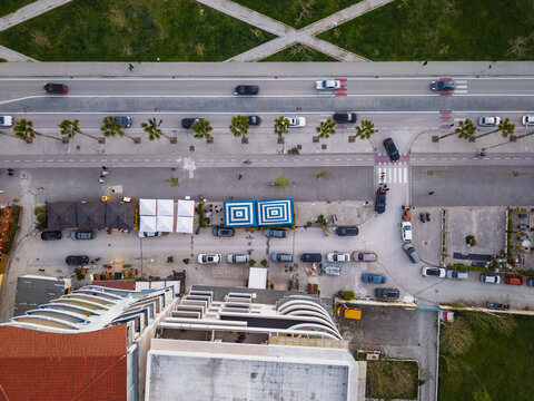 Aerial view of the coastal street in Vlora featuring palm trees, parked cars, and buildings with rooftops in Vlora, Vlore County, Albania.