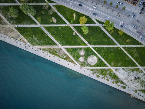 Aerial view of a geometric park with green lawns and intersecting paths along the waterfront promenade in Vlora, Vlore County, Albania.