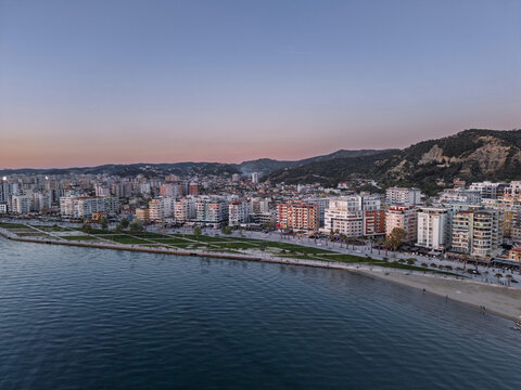 Aerial view of the Vlora coastline featuring modern apartment buildings, a sandy beach, and a promenade at sunset in Vlora, Vlore County, Albania.