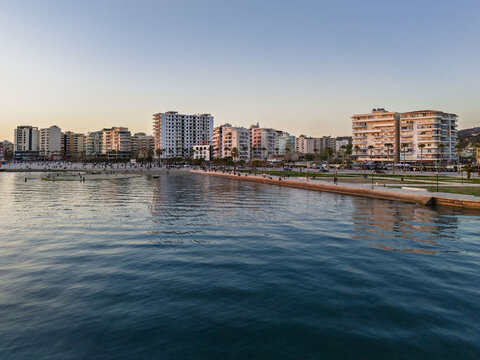 Aerial view of the coastal city of Vlora with modern apartment buildings along the waterfront, promenade, and calm sea in Vlora, Vlore County, Albania.