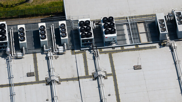 Aerial view of industrial rooftop featuring multiple HVAC cooling units, ventilation pipes, and metal walkways in Nieuwegein, Utrecht, Netherlands.