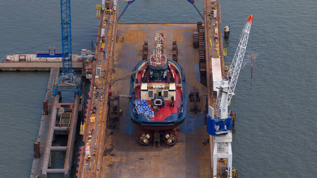 Aerial view of a tugboat undergoing maintenance in a dry dock at Damen Shiprepair Oranjewerf in Amsterdam, Noord-Holland, Netherlands.