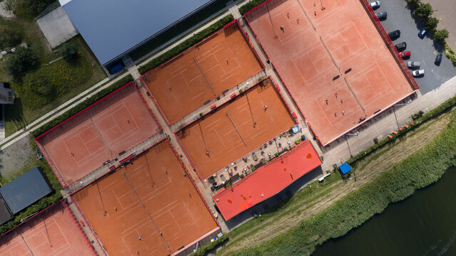Aerial view of Tennisclub IJburg with red clay tennis courts and players in action situated near the water in Amsterdam, Noord-Holland, Netherlands.