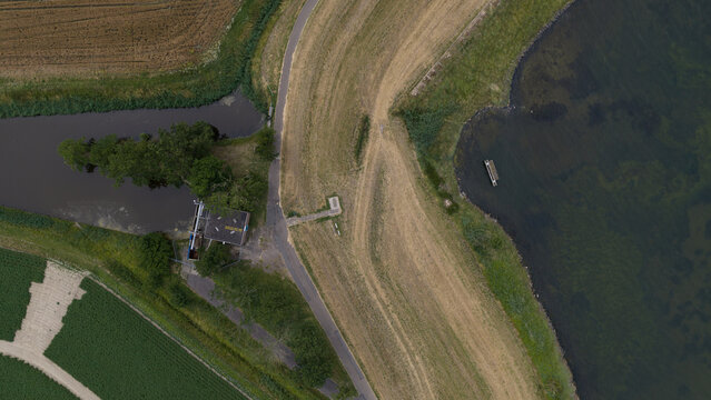 Aerial view of a canal and small sluice structure surrounded by agricultural fields and a path in Wilhelminadorp, Zeeland, Netherlands.