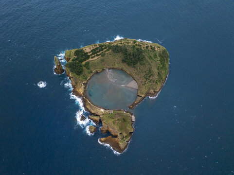 Aerial view of Ilheu de Vila Franca do Campo, a volcanic islet with a central circular lagoon surrounded by the Atlantic Ocean, featuring rocky cliffs, Sao Pedro, Acores, Portugal.