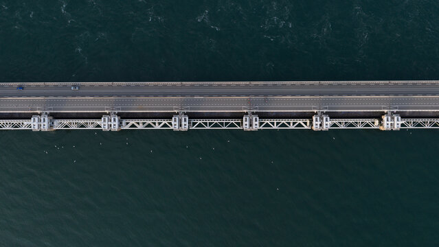 Aerial view of the Eastern Scheldt Storm Surge Barrier with its massive steel gates and road bridge spanning the dark water in Vrouwenpolder, Zeeland, Netherlands.