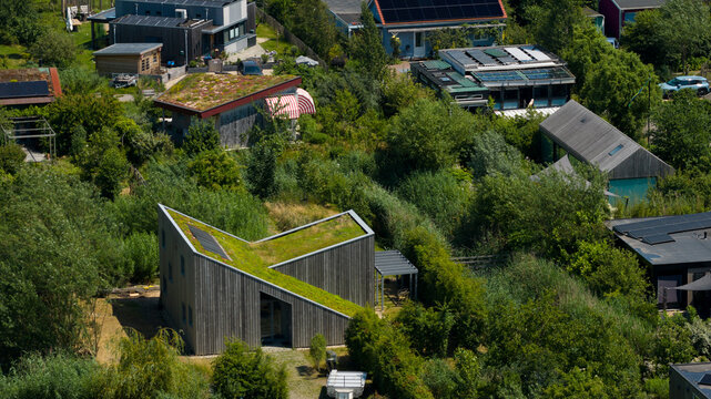 Aerial view of Ecodorp Bolderburen featuring sustainable modern houses with green roofs, wooden facades, and solar panels nestled within lush greenery in Almere, Flevoland, Netherlands.