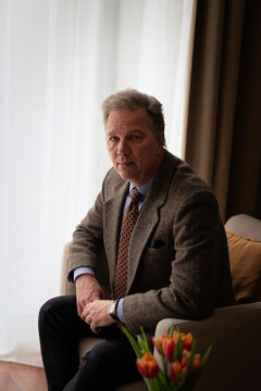 Confident man sitting on armchair at home and looking at the camera