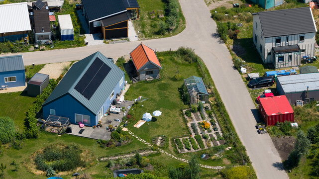 Aerial view of Ecodorp Bolderburen featuring sustainable homes with solar panels, lush gardens, and a greenhouse in a quiet residential neighborhood in Almere, Flevoland, Netherlands.
