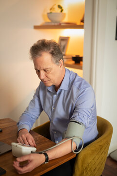 Senior man measuring blood pressure at home