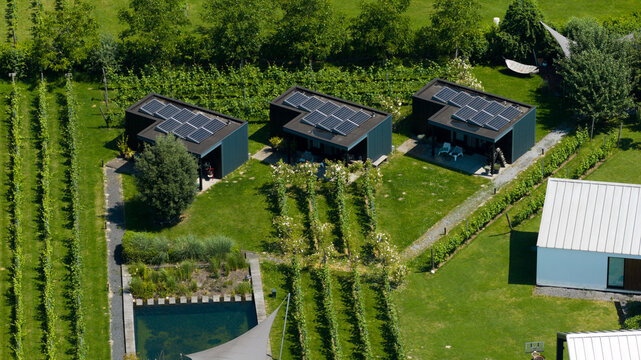 Aerial view of Ecodorp Bolderburen featuring modern sustainable houses with solar panels, lush green gardens, a swimming pool, and vineyard rows in Almere, Flevoland, Netherlands.