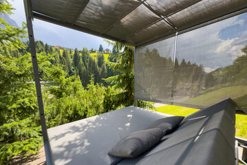 Obraz premium Awesome photo of cozy wooden balcony with comfortable lounge chair overlooking scenic green mountains. 