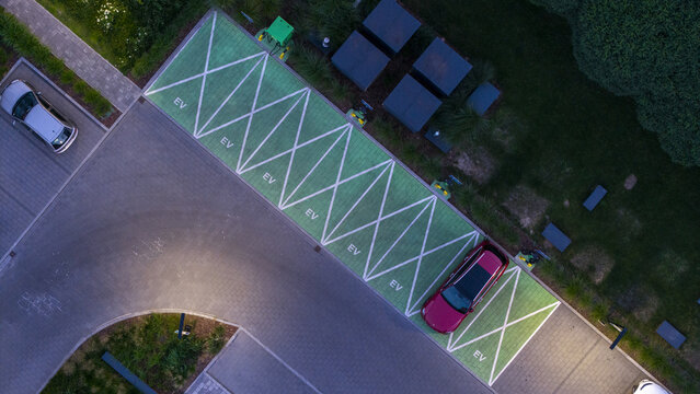 Aerial view of an electric vehicle charging station with green painted parking spaces and a red car parked in Poland.