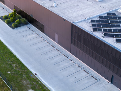 Aerial view of a modern industrial building with rooftop solar panels and an empty parking lot in Poland.