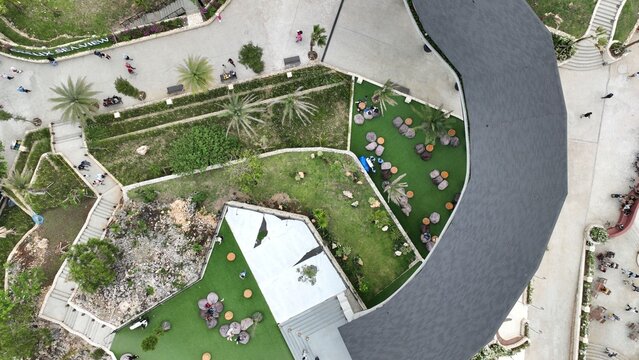 Aerial view of Obelix Sea View featuring a modern curved roof structure, landscaped green areas, outdoor seating, and pathways in Kecamatan Purwosari, Daerah Istimewa Yogya, Indonesia.