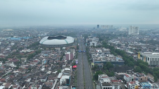 Aerial view of Patriot Candrabhaga Stadium surrounded by dense urban buildings and a major highway in Bekasi Barat, West Java, Indonesia.