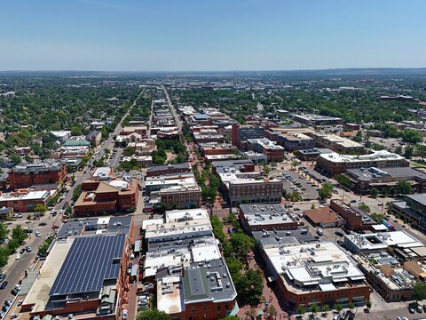 Aerial view of Pearl Street Mall in downtown Boulder, featuring historic brick buildings, solar panels, lush trees, and urban street layout in Boulder, Colorado, United States.