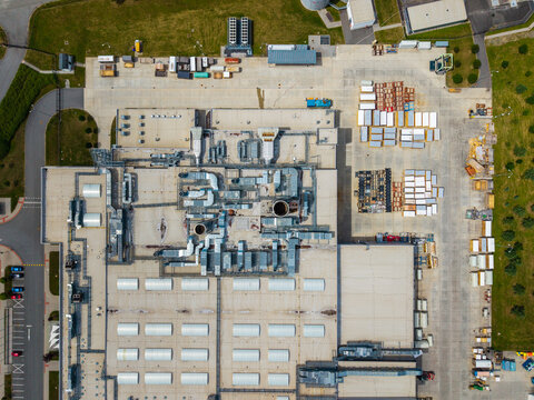 Aerial view of an industrial facility with rooftop ventilation systems, skylights, and a storage yard with containers in Zebrak, Central Bohemian Region, Czechia.